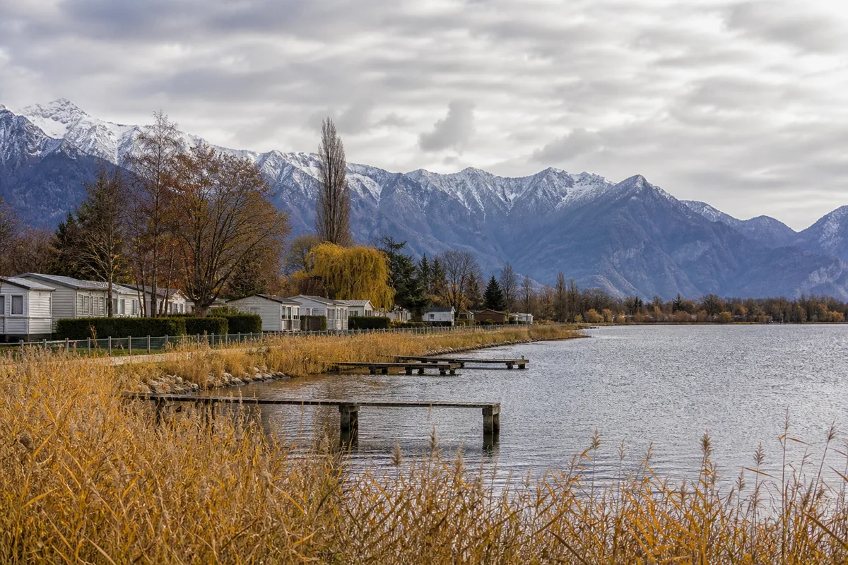 Rives boisées du lac d&rsquo;Annecy à l&rsquo;automne, campings fermés et montagnes en arrière-plan