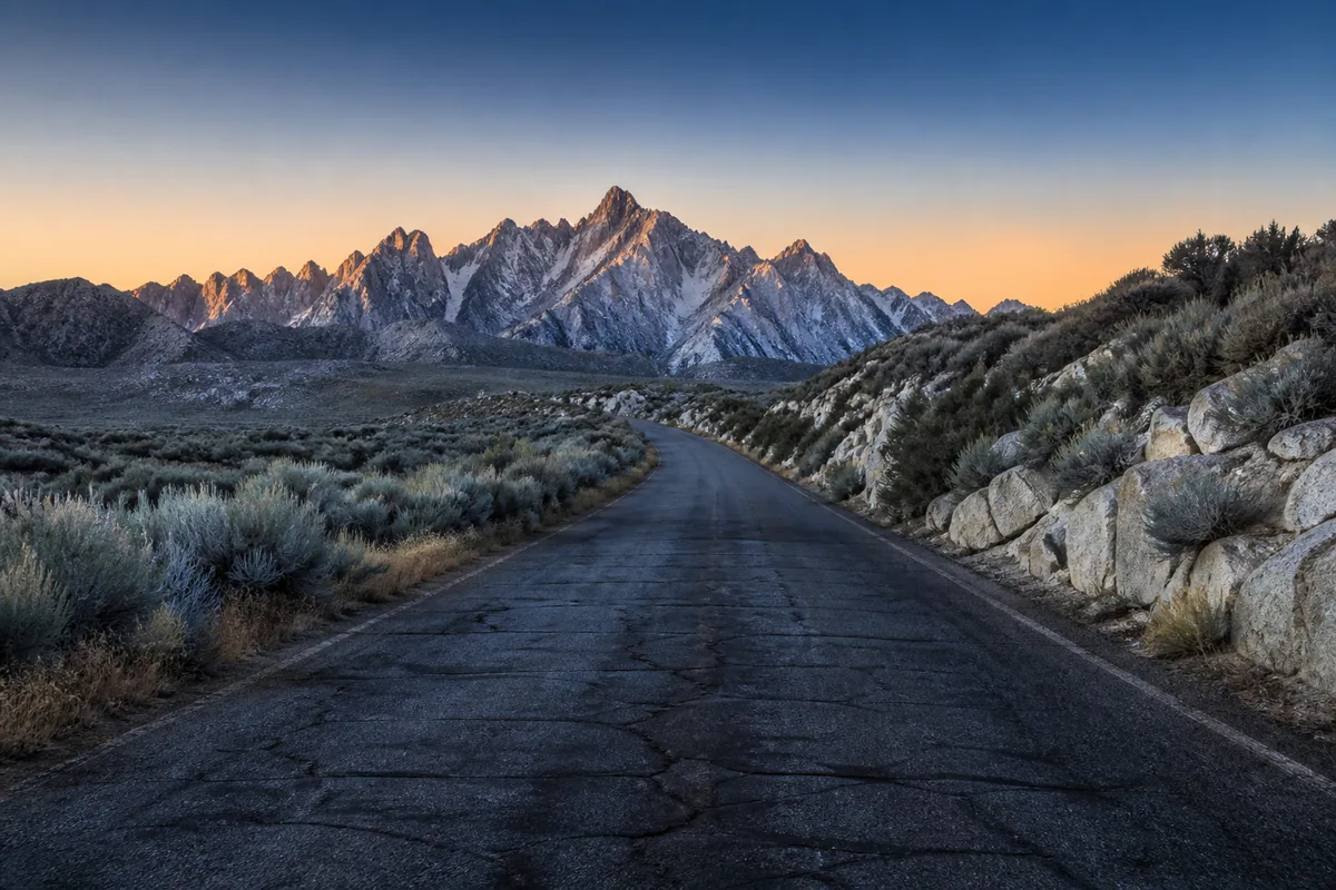 Route de montagne au lever du jour menant vers l&rsquo;entrée d&rsquo;un parc national, sauge argentée sur les bas-côtés